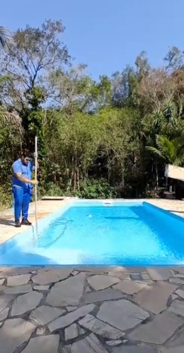 Piscina de azulejo após o serviço de manutenção, sendo aspirada para remoção de sujeira.